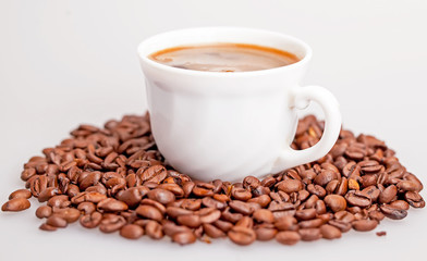 Coffee beans scattered around a cup of coffee.