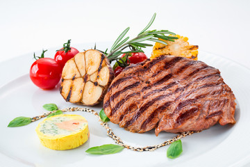 Grilled meat steak with vegetables in a plate on a white background