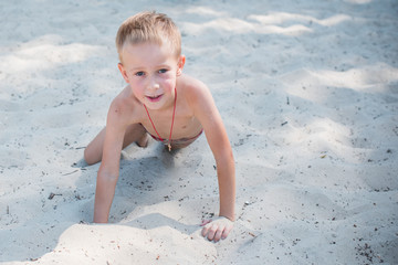 Boy  playing on the beach on summer holidays. Children in nature with beautiful sea, sand and blue sky. Happy kids on vacations at seaside in the water 