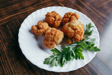 fried fresh cauliflower in breadcrumbs closeup on a plate.