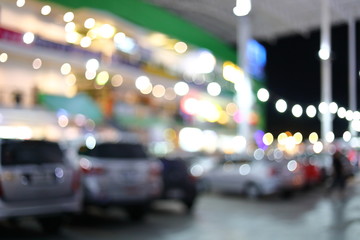 blur night light in business building with car park, abstract blurry bokeh of city background