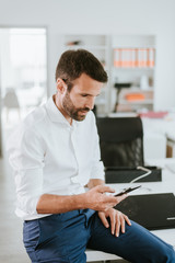 Fototapeta premium Manager on his phone. Man at work sitting on a desk while talking on the phone.