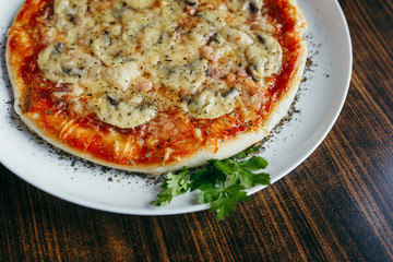 Hot pizza slice with melting cheese on a wooden table.