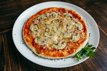 Hot pizza slice with melting cheese on a wooden table.