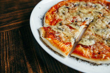 Hot pizza slice with melting cheese on a wooden table.