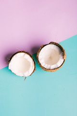 Coconut on a blue and pink background with space for text. Half of coconut on turquoise and pink background. Tropical fruit concept.