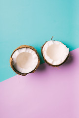 Coconut on a blue and pink background with space for text. Half of coconut on turquoise and pink background. Tropical fruit concept.