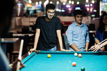 Group of stylish asian friends wear on jeans playing pool billiard on bar.