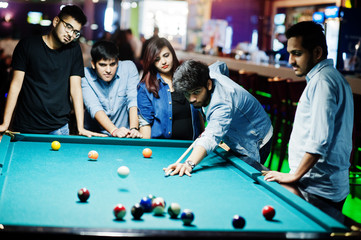 Group of stylish asian friends wear on jeans playing pool billiard on bar.