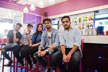 Obraz premium Group of stylish asian friends wear on jeans sitting at chairs against bar in club.