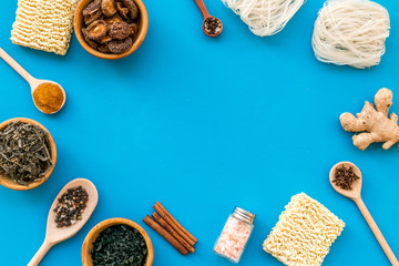 Rice vermicelli, noodles, spices, weeds frame to cook Chinese and Japanese food on blue background top view copy space