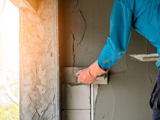 plasterer concrete worker at wall of house construction site