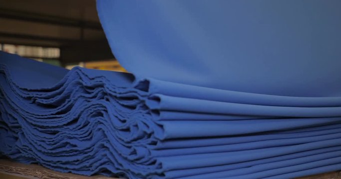 The garment factory takes a sample of a roll of blue fabric checking the quality of the roll checking on the machine the roll of fabric is unwound fully. Concept of: Checking quality, New fabric.