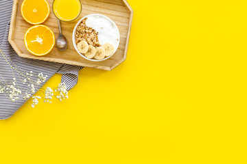 Healthy granola with banana and orange juice for colorful breakfast on yellow background top view mock-up
