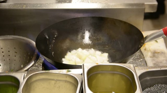 Close up someone cooking in wok pan. Vegetable curry being seasoned with spices