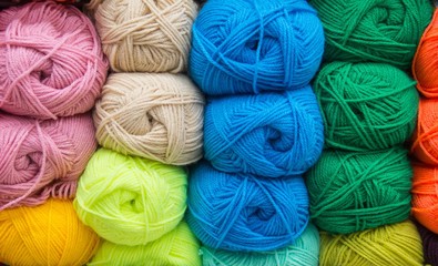 Multi-colored yarn. Yarn is beige, brown, grey and white. Knitting needles, scissors, coffee, knitting, knitted fabric.