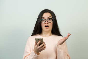 Young beautiful woman using mobile phone studio on white color background. Looking attentively at screen of cellphone, browsing web pages.