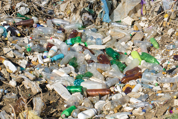 Plastic bags and bottles in a landfill. Unauthorized release of garbage, pollution of nature. The concept of environmental disaster.