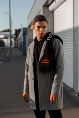 Handsome guy in stylish clothes walks on a city street at sunset