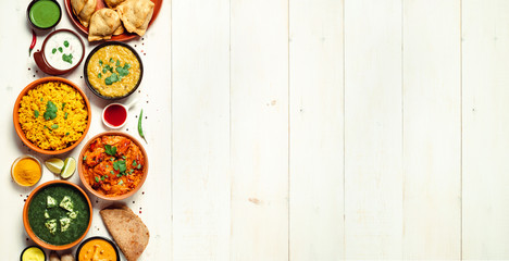 Indian cuisine dishes: tikka masala, dal, paneer, samosa, chapati, chutney, spices. Indian food on white wooden background. Assortment indian meal banner with copy space for text. Top view or flat lay