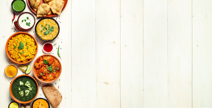 Indian cuisine dishes: tikka masala, dal, paneer, samosa, chapati, chutney,  spices. Indian food on white wooden background. Assortment indian meal  banner with copy space for text. Top view or flat lay Stock