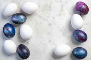 Easter eggs with cosmic pattern and white Easter eggs on the marble surface