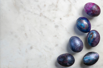Easter eggs with cosmic pattern and white Easter eggs on the marble surface