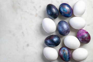 Easter eggs with cosmic pattern and white Easter eggs on the marble surface