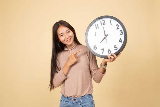 Young Asian woman point to a clock.