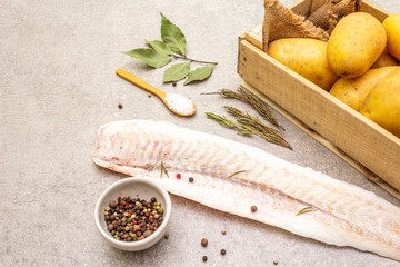 Raw young potatoes and frozen hake fillets. Ingredients for fish and chips. Spices and herbs on a...