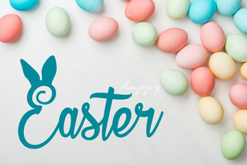 top view of multicolored chicken painted eggs on grey background with happy Easter blue lettering