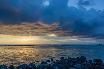 Spectacular evening seascape with low clouds illuminated by beams of the sunset sun, Mauritius island