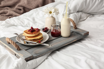 Fototapeta na wymiar Board with tasty breakfast on bed