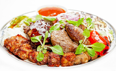 A plate with meat dishes, kebabs, bishtex, sauces and various croutons.