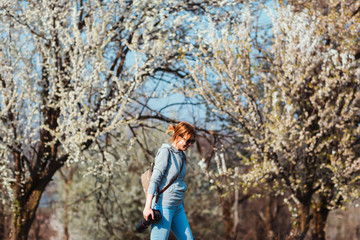Girl photographer enjoying spring day in nature with a blooming cherry tree.