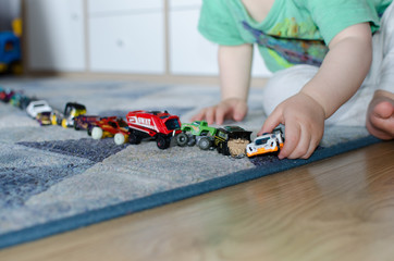 Child lining up toys on the floor at home.