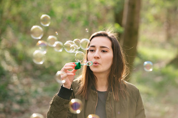 Young woman blowing soap bubbles in the woods.
