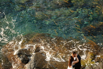 Romantic wedding couple posing on rocks near sea