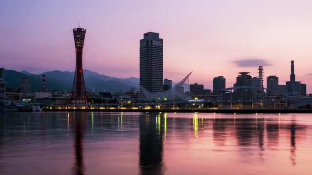 Kobe, Japan. View of sunrise in Kobe, Japan. Time-lapse of cloudless sky with harbor and numerous skyscrapers and Port Tower, zoom in