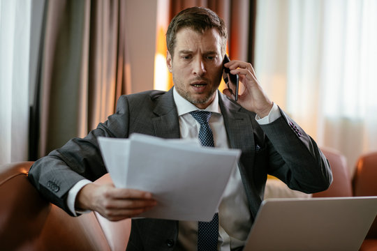 Manager on his phone, at a hotel room. Businessman gets ready for the meeting.