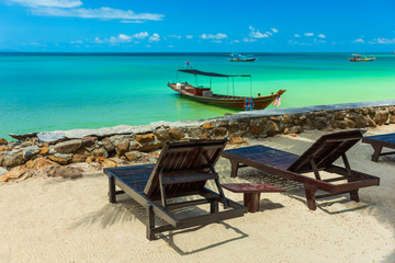 Fototapeta na wymiar Tropical resort with chaise longs under palms on sandy beach
