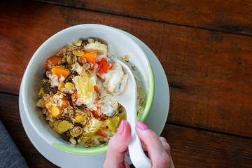 Yellow corn flakes and a glass of milk for dry healthy breakfast. Top view. Cereals spoon and bowl in hands
