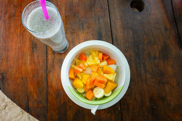 Mixed fruit salad in the bowl on wooden background