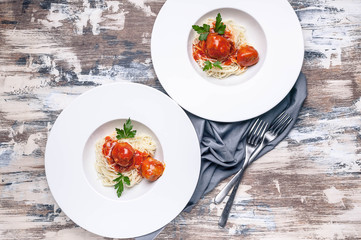 Top view meatballs in tomato sauce with basil and cardamom with spaghetti on large white plates