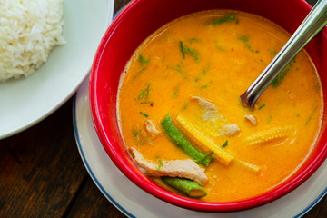 Thai yellow curry soup with rice on rustic table