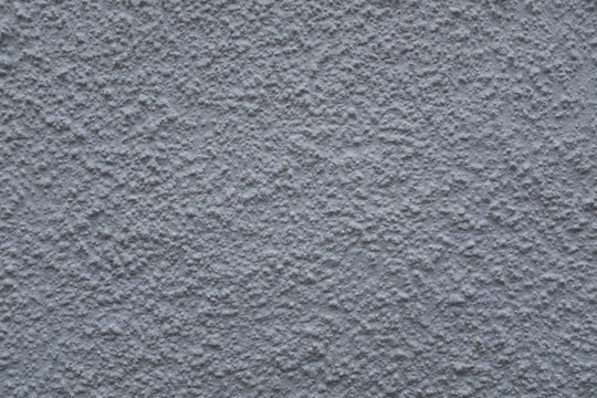 A close up photo of an exterior  textured wall painted gray textured, surface with stucco daub, great for background images