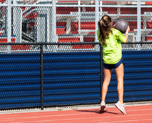 Teenage girl throwing med ball overhead backwards