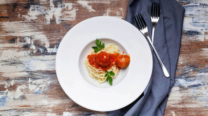 Top view spaghetti and meatballs in tomato sauce on a white plate