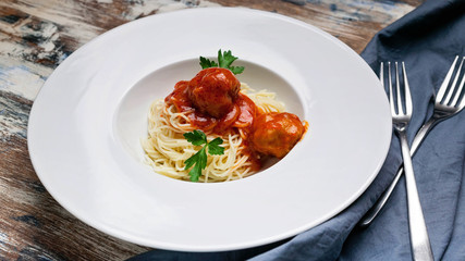 Spaghetti and meatballs in tomato sauce on a white plate