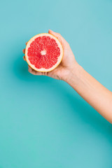 Fresh grapefruit  on pastel background. Hand holding citrus fruit.